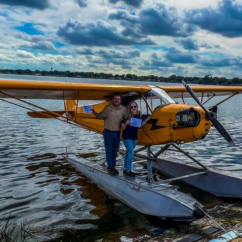 Kyla Hampson and her father stand next to a sea plane after she received her sea plane rating.