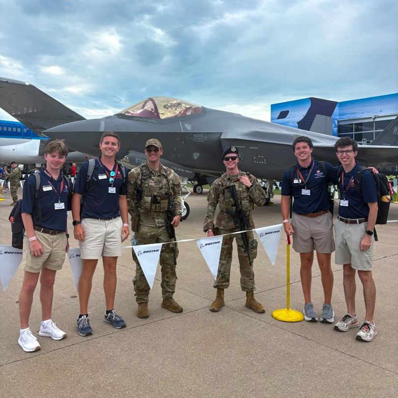 Four Striped Wing Ambassadors stand in front of a Boeing Aircraft