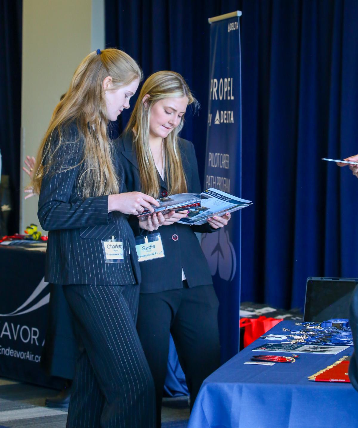 Two female aviation students inspect Republic Airways program and merchandise.