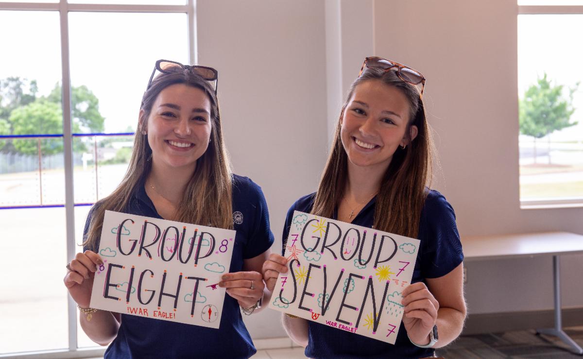 Two Ninety-Nines members hold signs that read "Groups Seven" and "Group Eight"