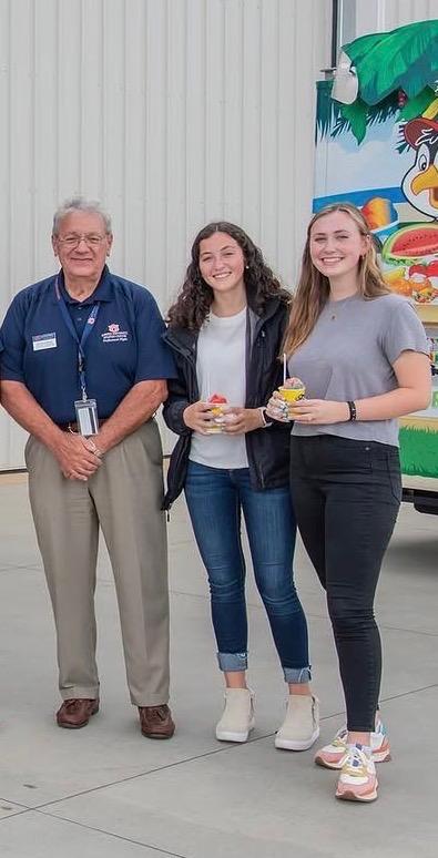 Wayne Ceynowa stands next to two auburn students, while smiling at the camera.