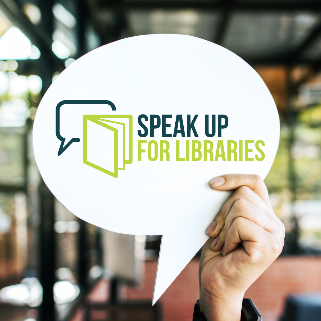 Hand holding a sign in the shape of a speech bubble with the Speak Up For Libraries logo on it with a book icon overlapping a speech bubble icon.