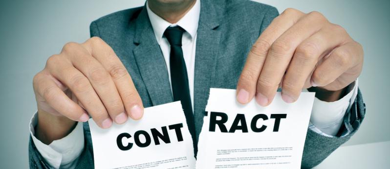 man wearing a suit sitting in a table ripping up a contract