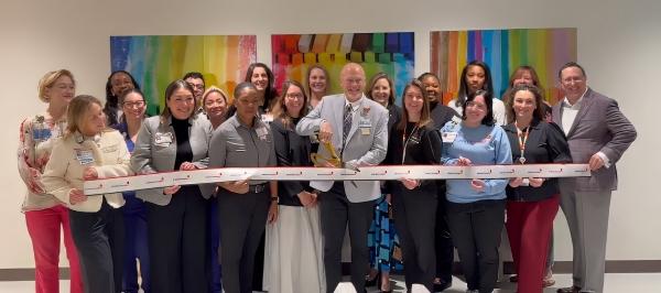 Dr. Norcross cuts a ribbon surrounded by a large group of people