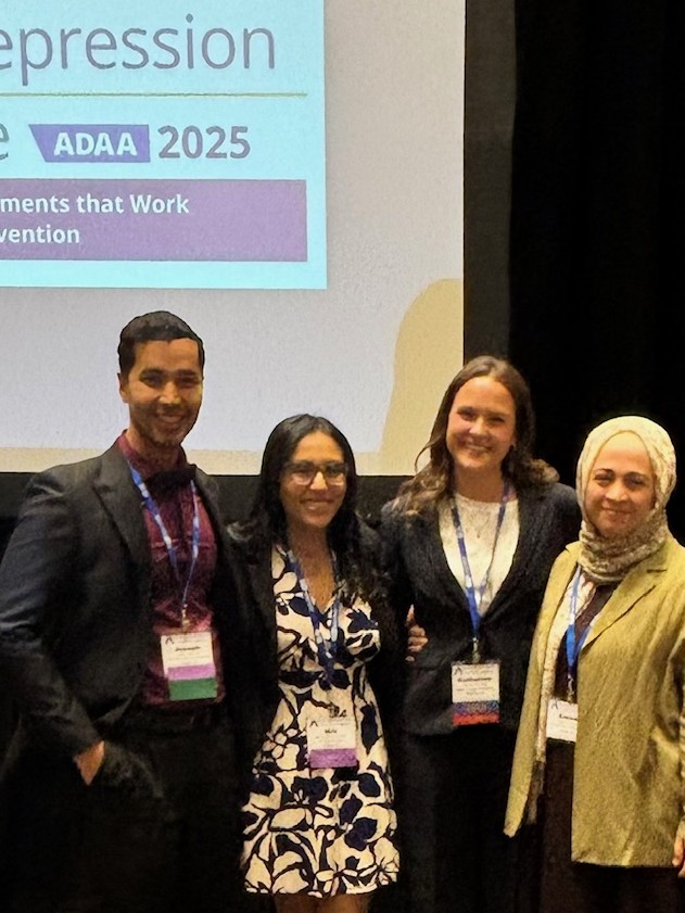 four people in front of a presentation screen