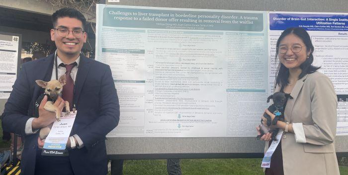 Drs Dong and Zarate Jarquin holding puppies in front of their poster