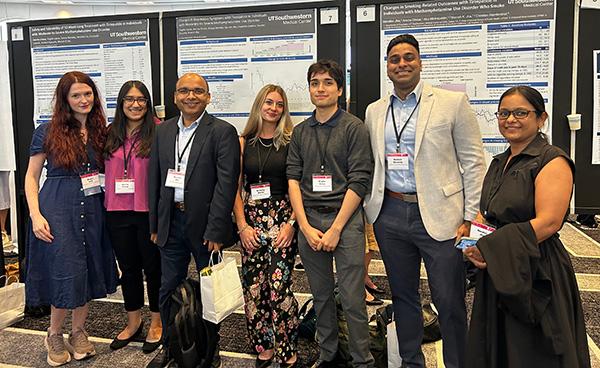 A group of people stand in front of research posters at the 2026 Annual Meeting of the American Society of Clinical Psychopharmacology. 