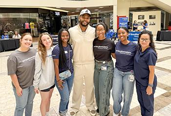 A group of psychology doctoral students pose with a Dallas Cowboy in the middle