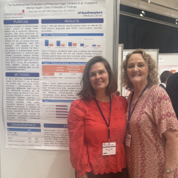 Two doctors stand in front of a research poster
