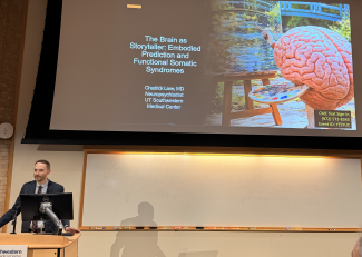 Dr. Chadrick Lane stands in front of a slide presentation about FND during a presentation in Baltimore