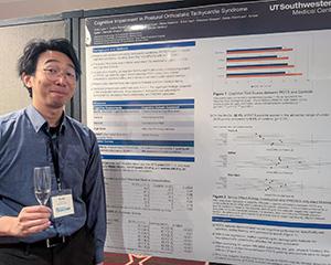 Victor Liaw stands in front of a poster at the American Neuropsychiatric Association event in March