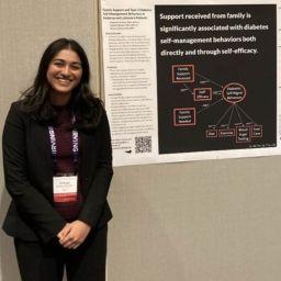Shivani Raman standing in front of her poster