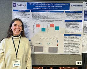 Victoria Ragland stands in front of a poster at the American Neuropsychiatric Association event in March