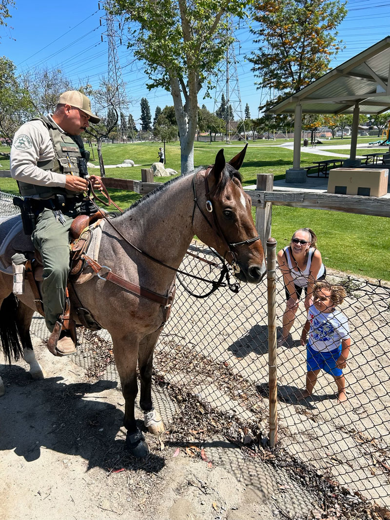 Deputy on horse talks to woman and child on trail