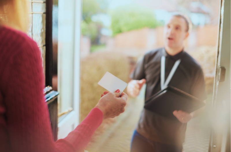 Solicitor at door hands woman a business card