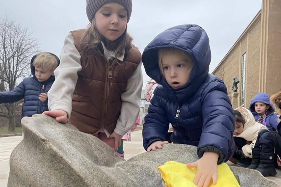Photograph of students wiping a sculpture to prepare it for winter at Cranbrook.