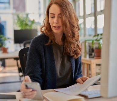 Businesswoman checking her phone while working at her office desk