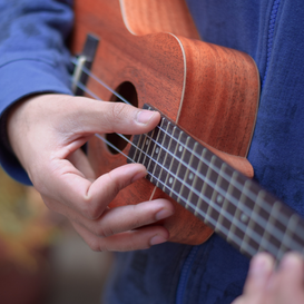 Ukulele with hands playing it