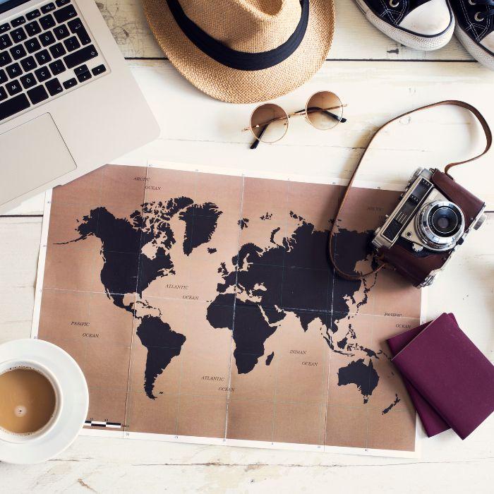Photo of map with camera hat sneakers a laptop and a cup of coffee