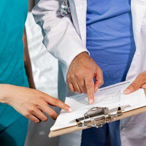 two people in scrubs pointing at a chart