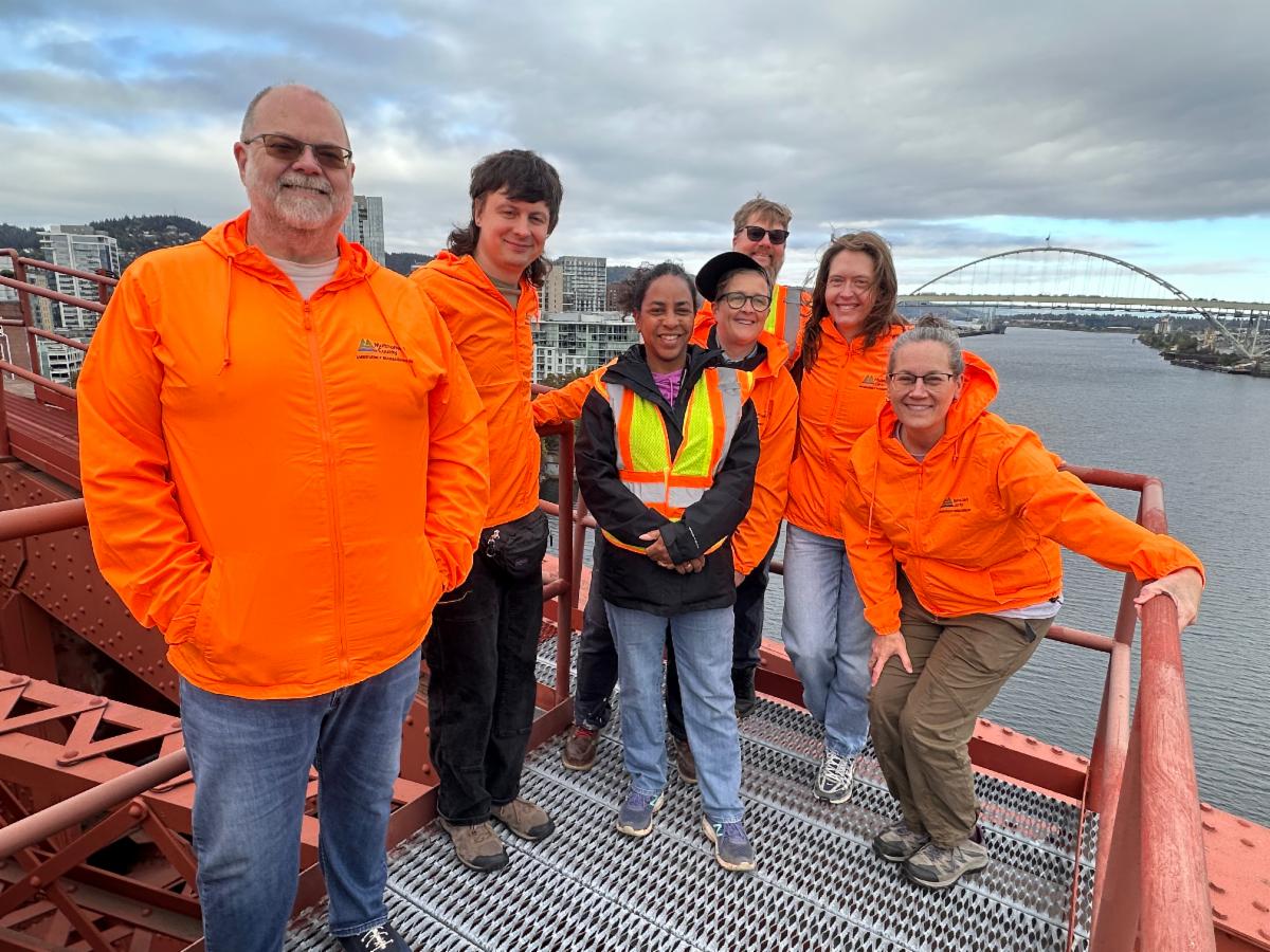 Seven MCEM staff members stand smiling on a bridge.