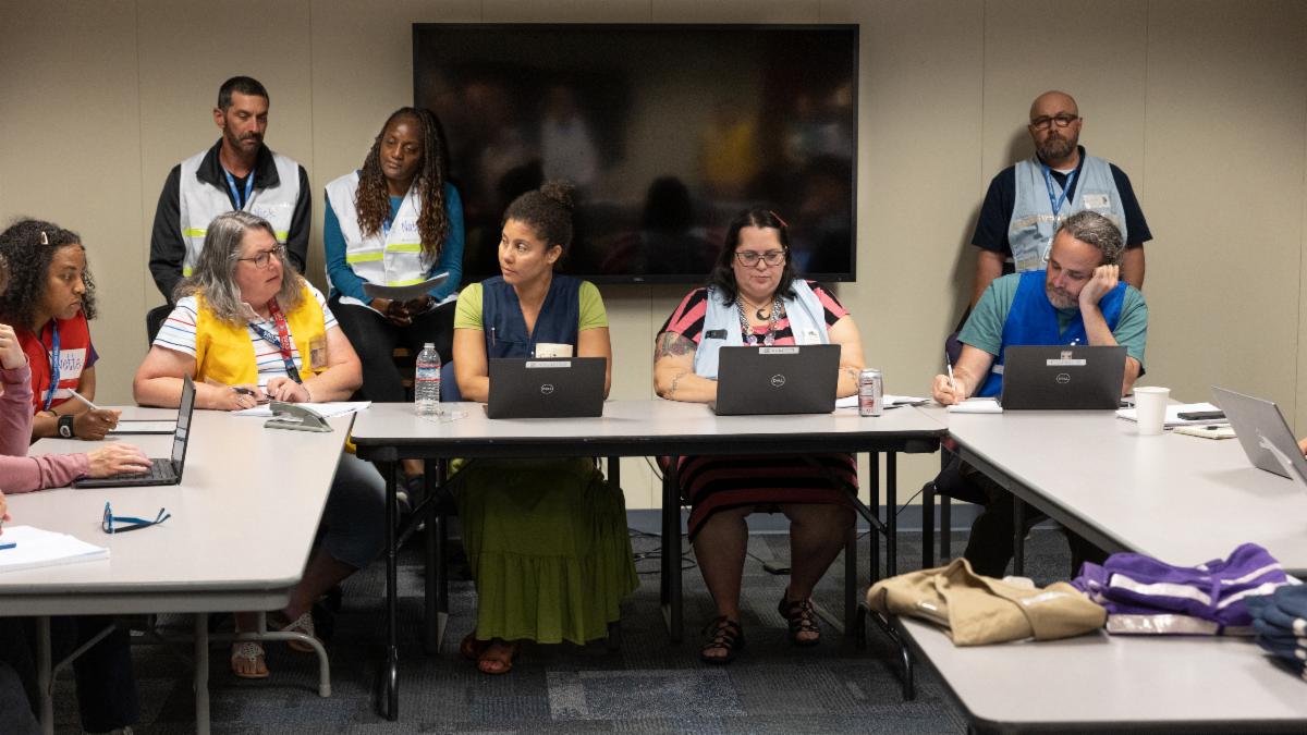 A Cascadia exercise briefing with Planning, Ops, and Logistics. Evaluators in white vests look on.