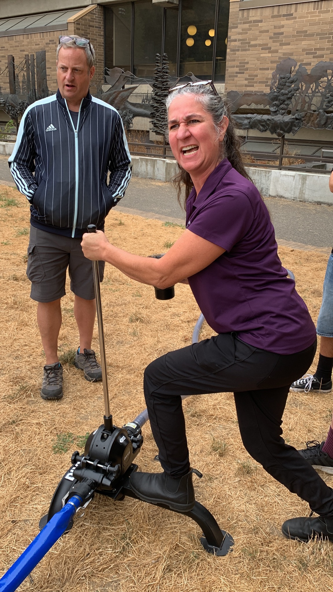 MCEM Operations employee Alice Busch takes a turn using the water filtration pump as MCEM Logistics Division Lead Matt Burke looks on.
