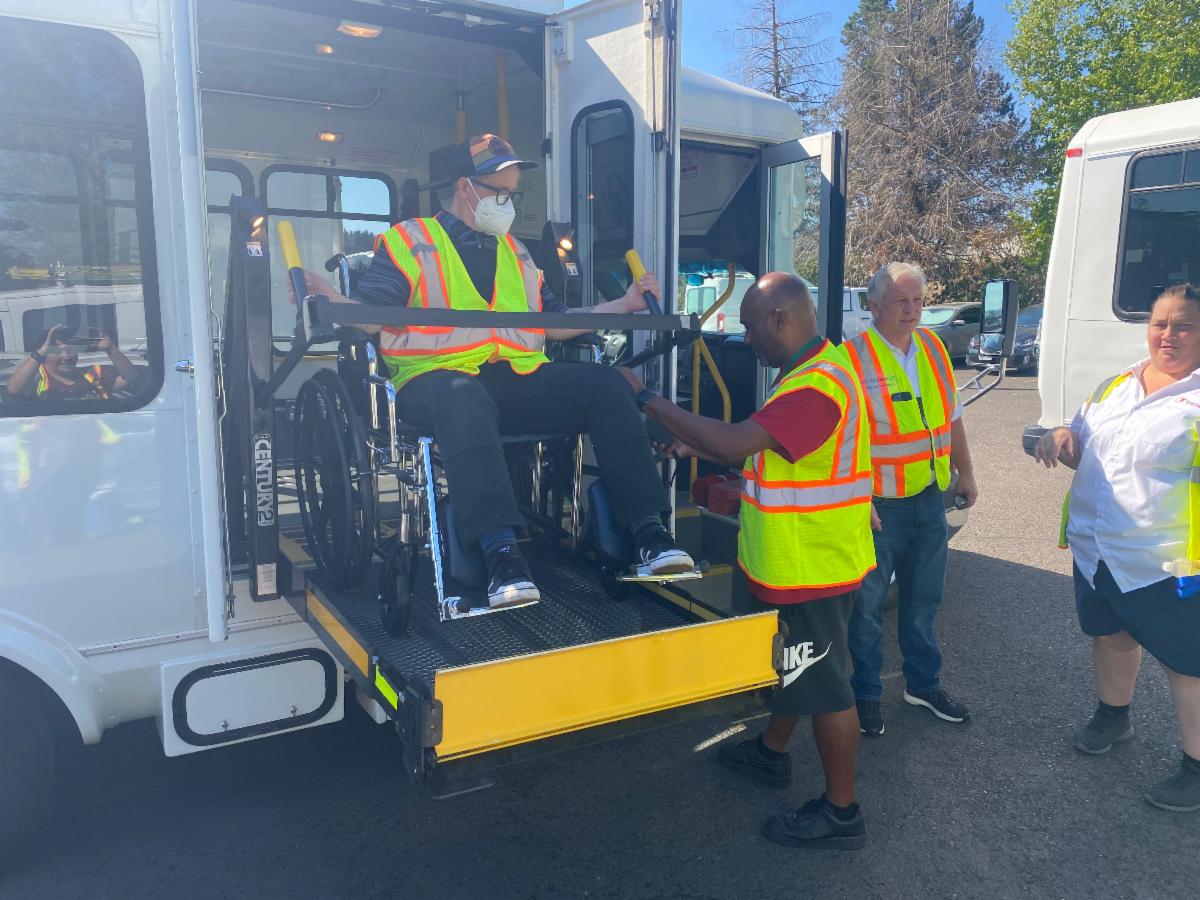 Several people being trained on how to use a LIFT bus wheelchair lift.