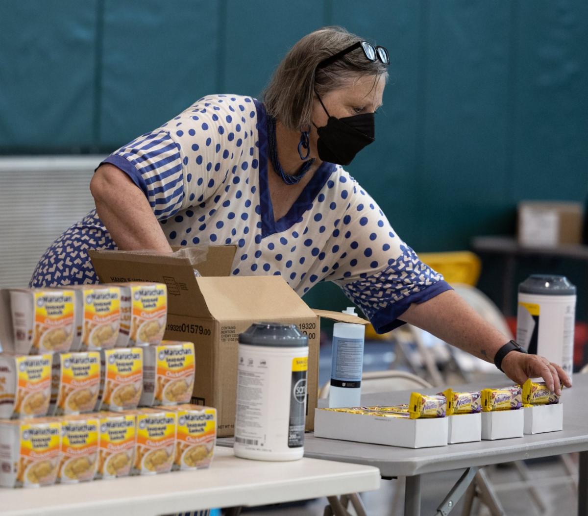 A person wearing a mask sets out snacks at an emergency shelter