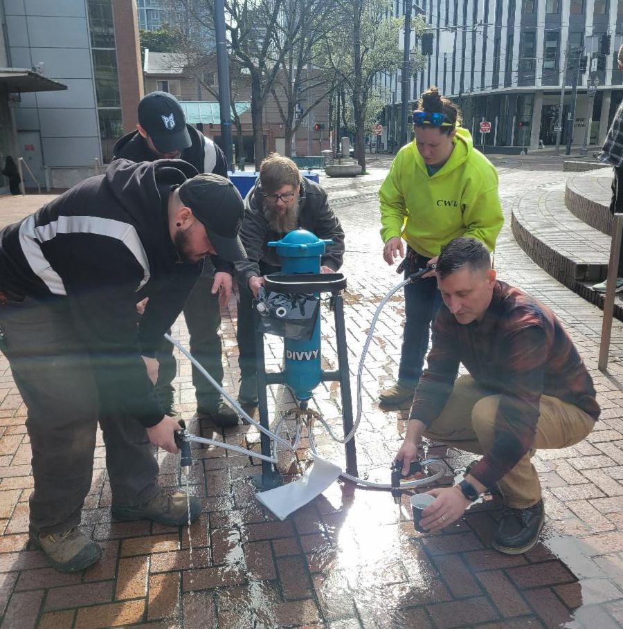 Partners from different organizations gather around the water filter system.