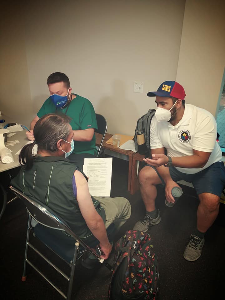 Three people sitting, including Marvin Peña, who is interpreting. All are wearing masks.
