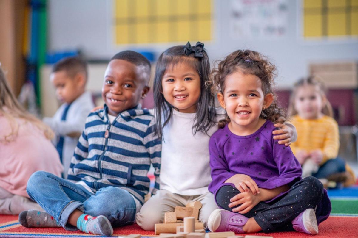 Three young children looking at the camera and smiling