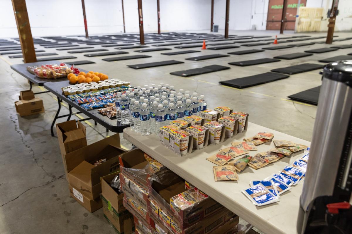 Water bottles, ramen cups and other snacks sit ready at an empty division place shelter.
