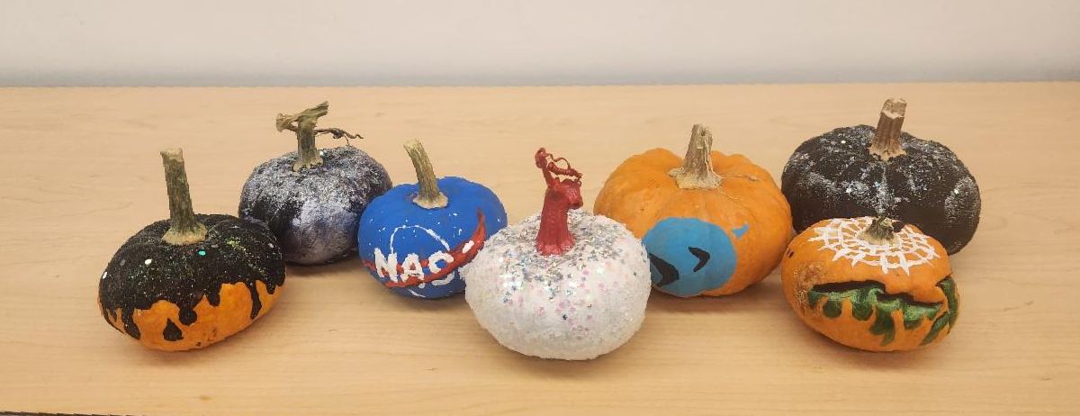A set of several small painted pumpkins with a space theme.