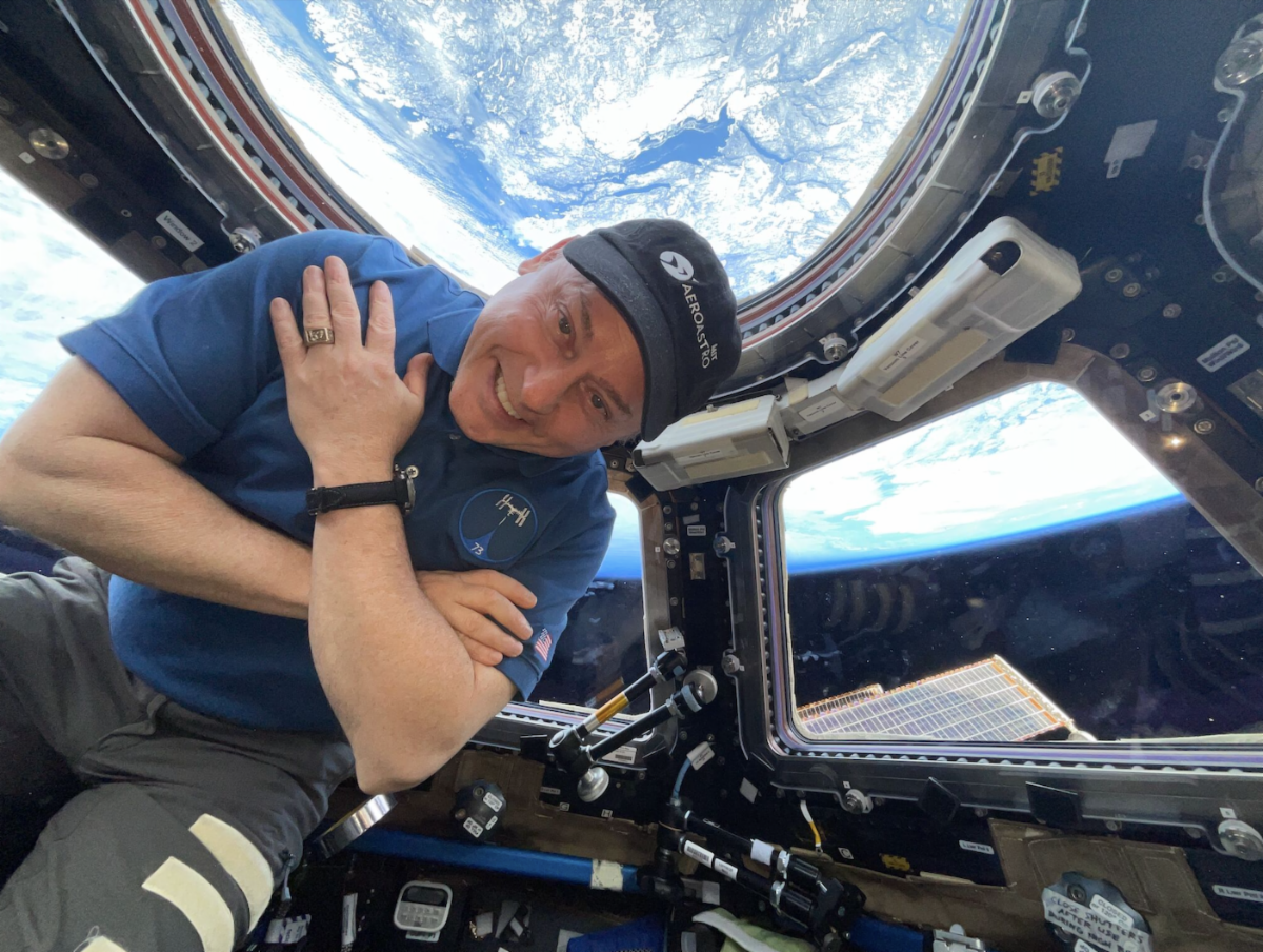 Person inside the International Space Station with Earth visible through a window.