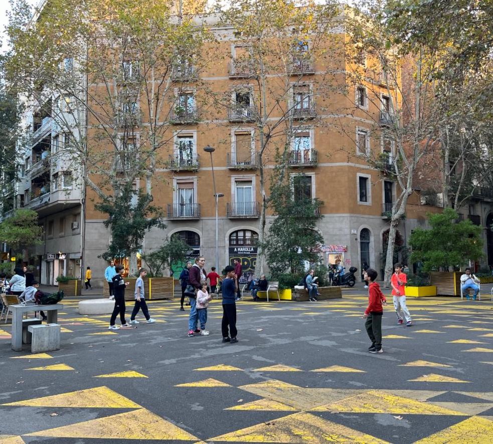 People gathering and children playing in the center of a re-designed intersection.