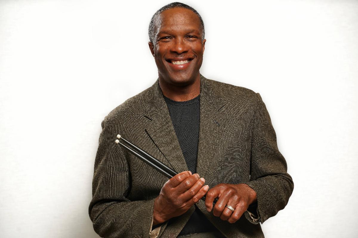 half-body headshot of Todd Kilgoe holding a set of drumsticks taken in front of a white background