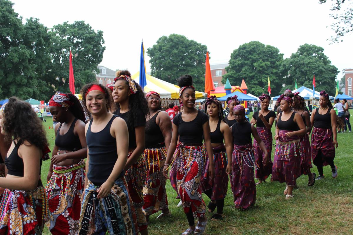 African American male and female teens wearing black tank tops and tee shirts and wrappers in traditional African prints walking in a processional in Dover as part of the African American Festival