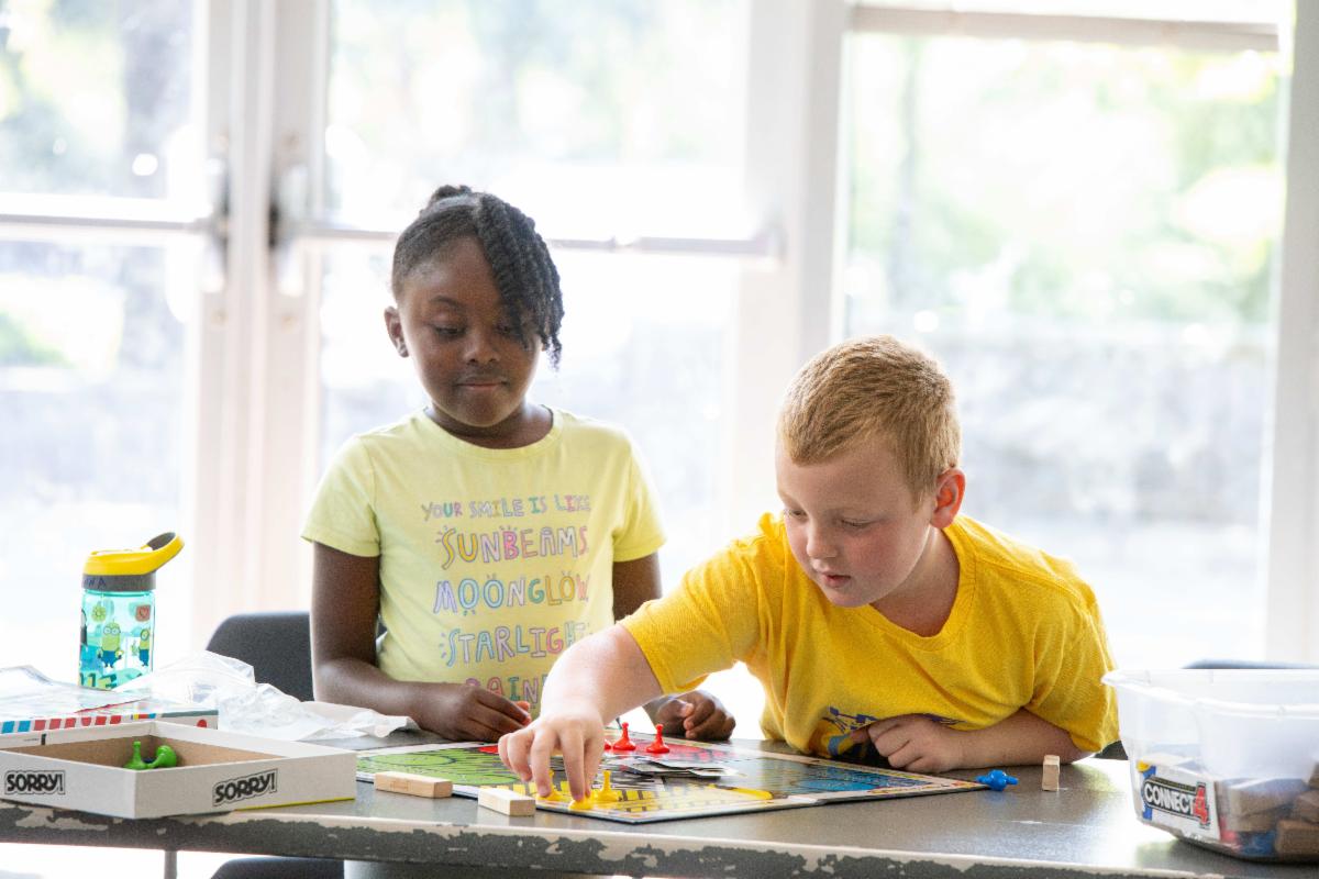 boy and girl playing a board game at summer camp