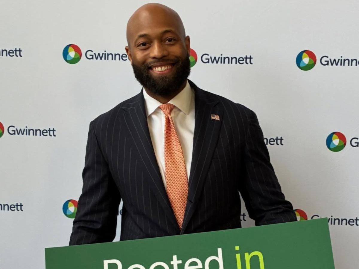 Commissioner Carden at State of the County even holding a green sign that says "Rooted in Gwinnett"