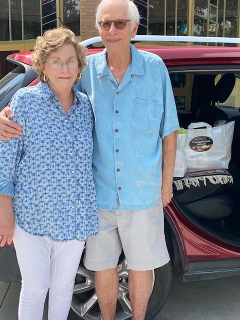 Image of an older woman and man smiling with delivery bags sitting on the car seat behind them