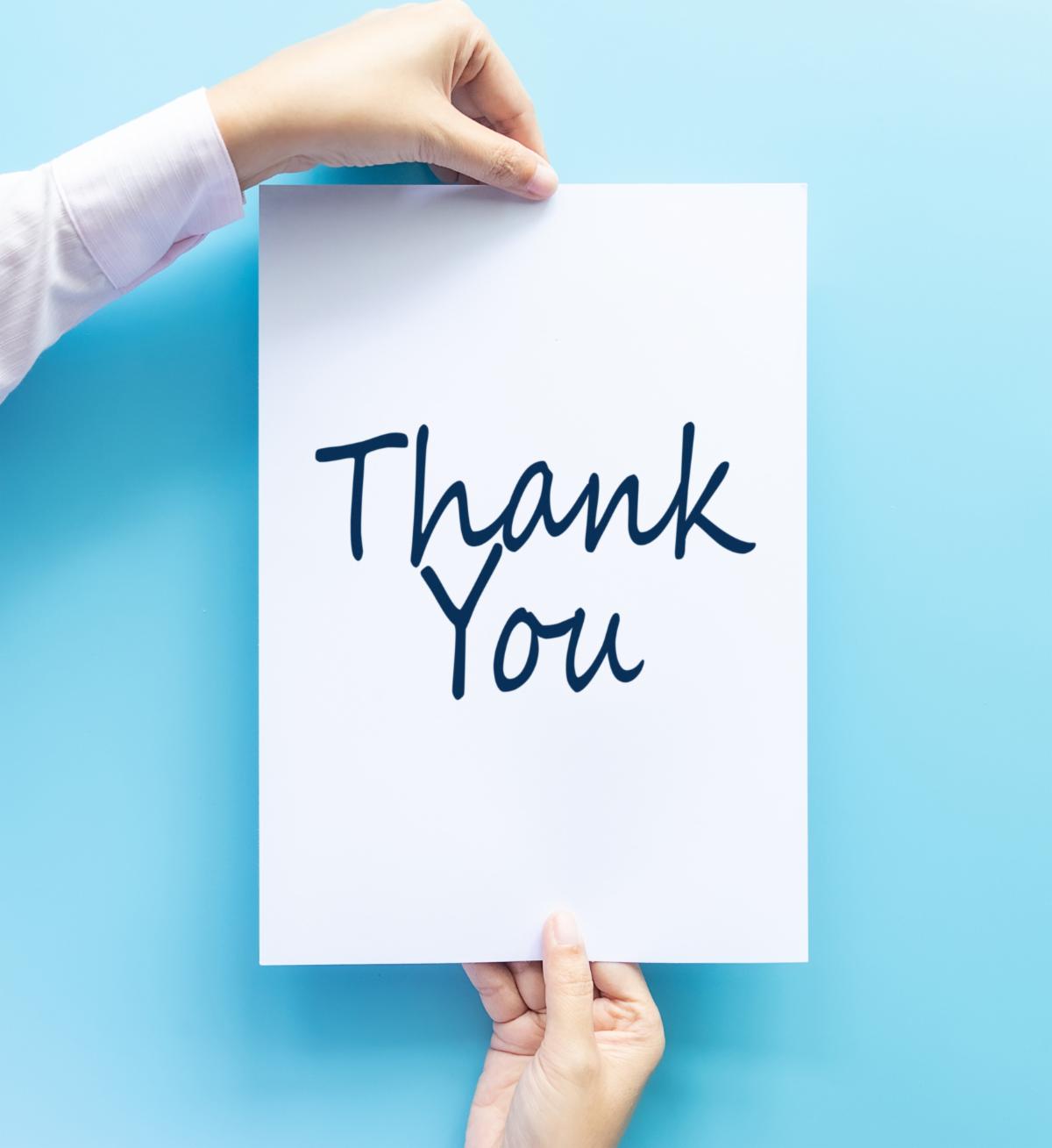 woman hand holding card with the word thank you isolated on blue background studio shot