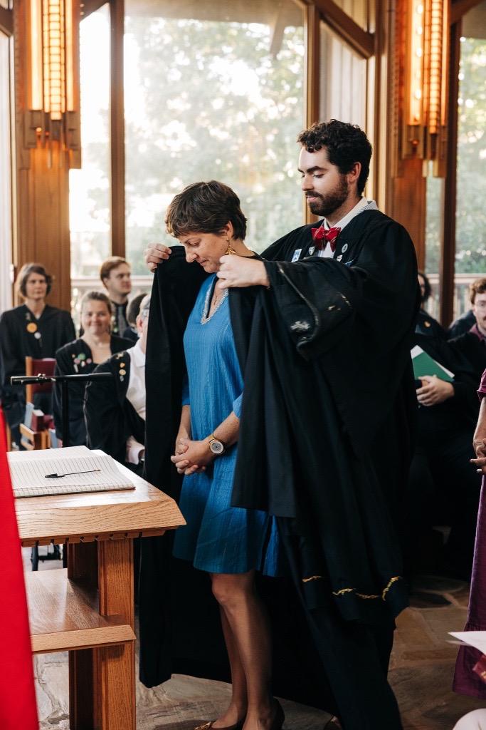 Sewanee Seminarian Wyatt Poe places a gown on Rebecca Segrest