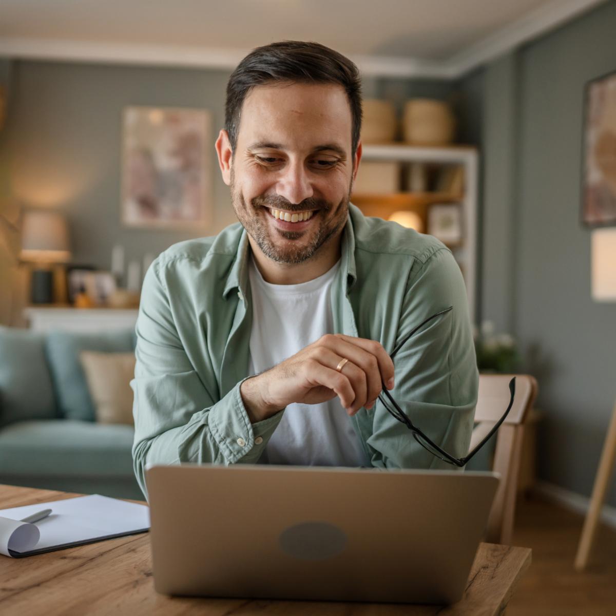 one man adult caucasian male with beard work on his laptop computer at home happy smile success freelance entrepreneur or remote work video call online concept