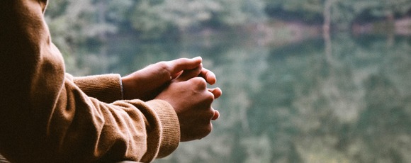 A woman with her eyes closed and hands over her heart, resting quietly at home