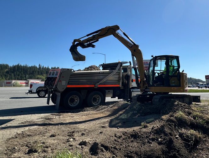 A loader emptying a bucket of dirt into a dump truck