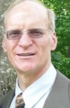 Headshot of Barry Blakely who is smiling and wears glasses and a suit and tie
