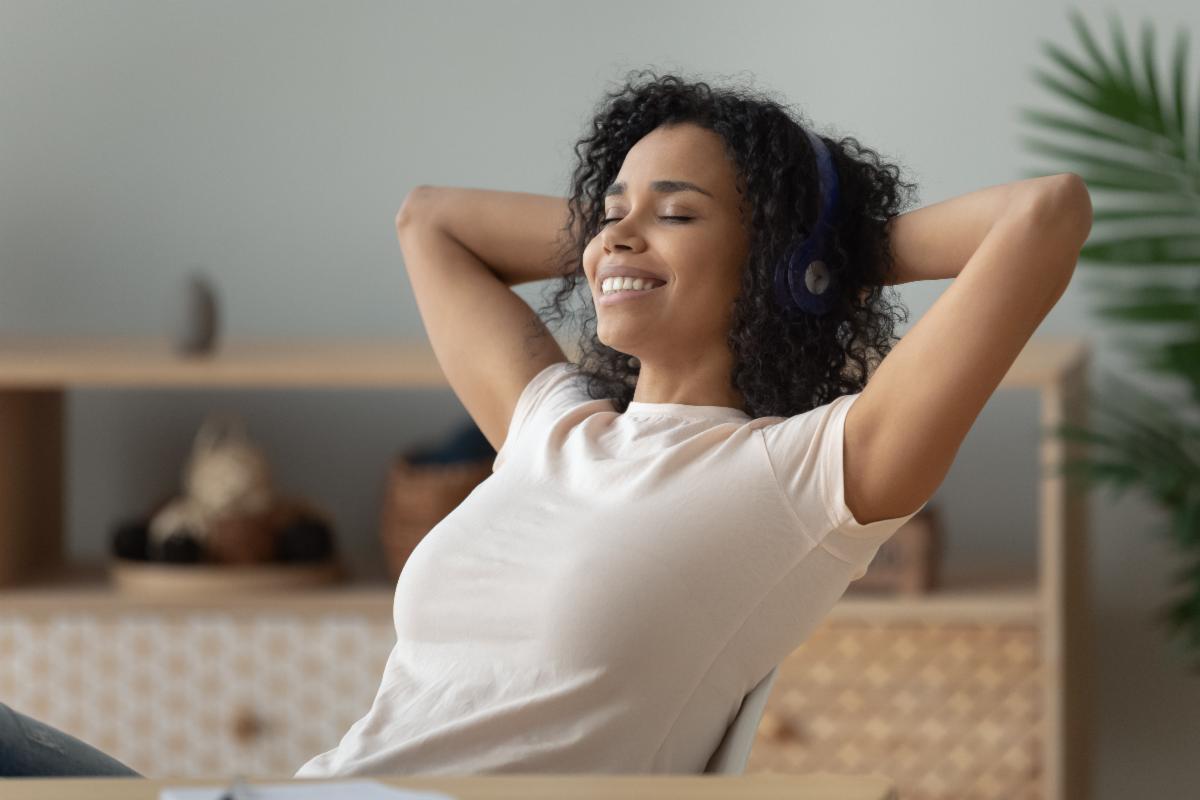 A person listening to music or something funny leans back in a chair and smiles contentedly