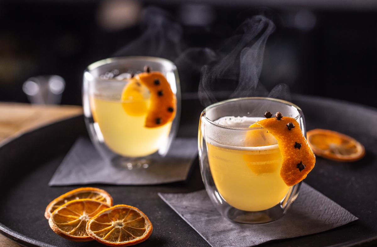 Two cups of steaming, hot tea with orange peel and cloves