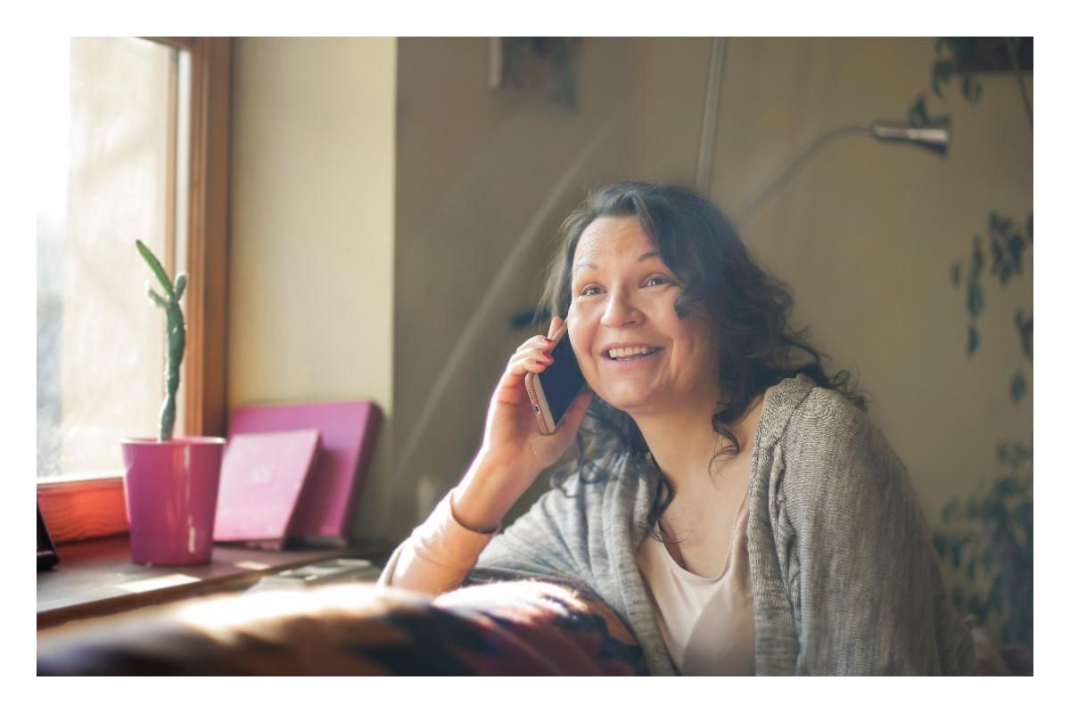 A parent talking on the phone while sitting in front of a window